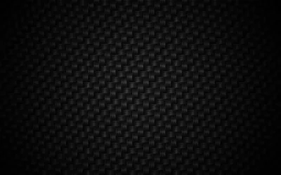 A carbon fibre weave repeats in tight diagonal blocks, the surface catching a faint sheen through the middle of the frame.