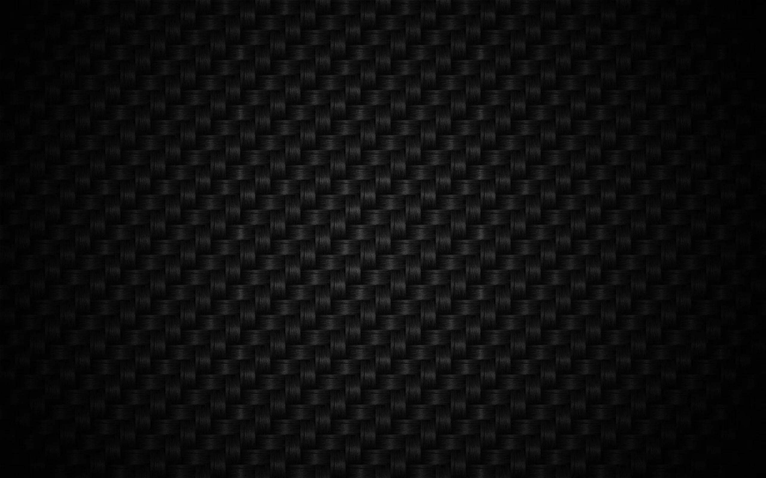 A carbon fibre weave repeats in tight diagonal blocks, the surface catching a faint sheen through the middle of the frame.