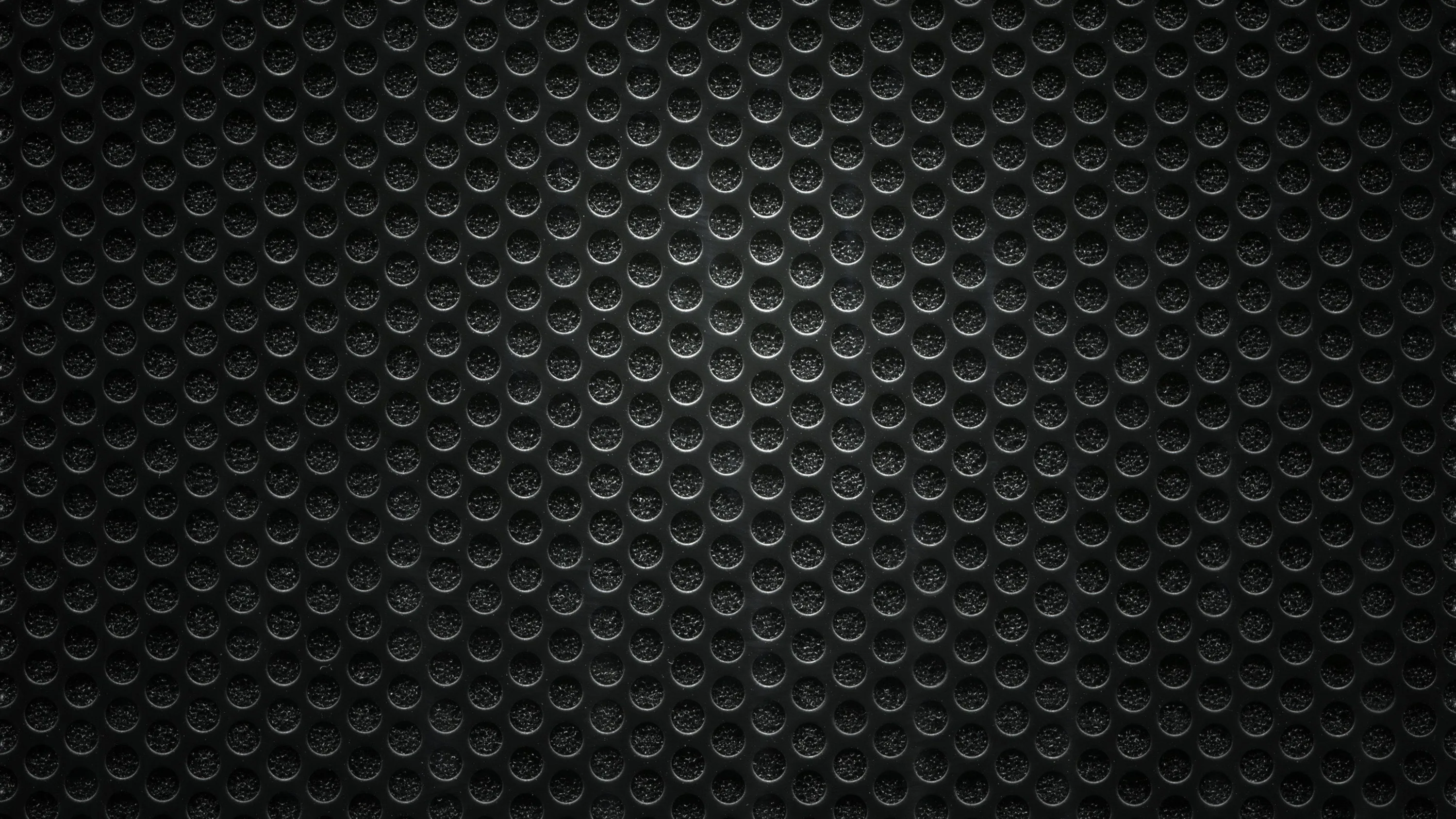 Rows of raised half-circles overlap like scales across a dark grey panel, the pattern brightest at the top and dimming toward the bottom.