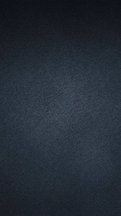 A close diagonal twill in blue-black cotton fills the frame, the weave finest in the centre and darkening toward the bottom.