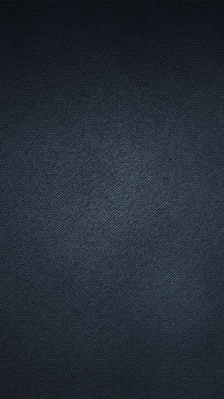 A close diagonal twill in blue-black cotton fills the frame, the weave finest in the centre and darkening toward the bottom.