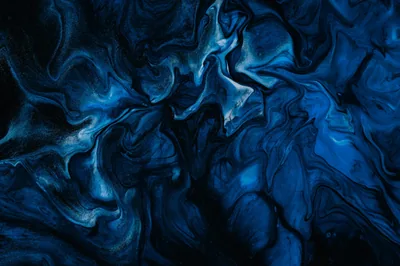 Ink swirls fold through each other in cobalt and navy, pale streaks marbling the upper left where the paint thins out.