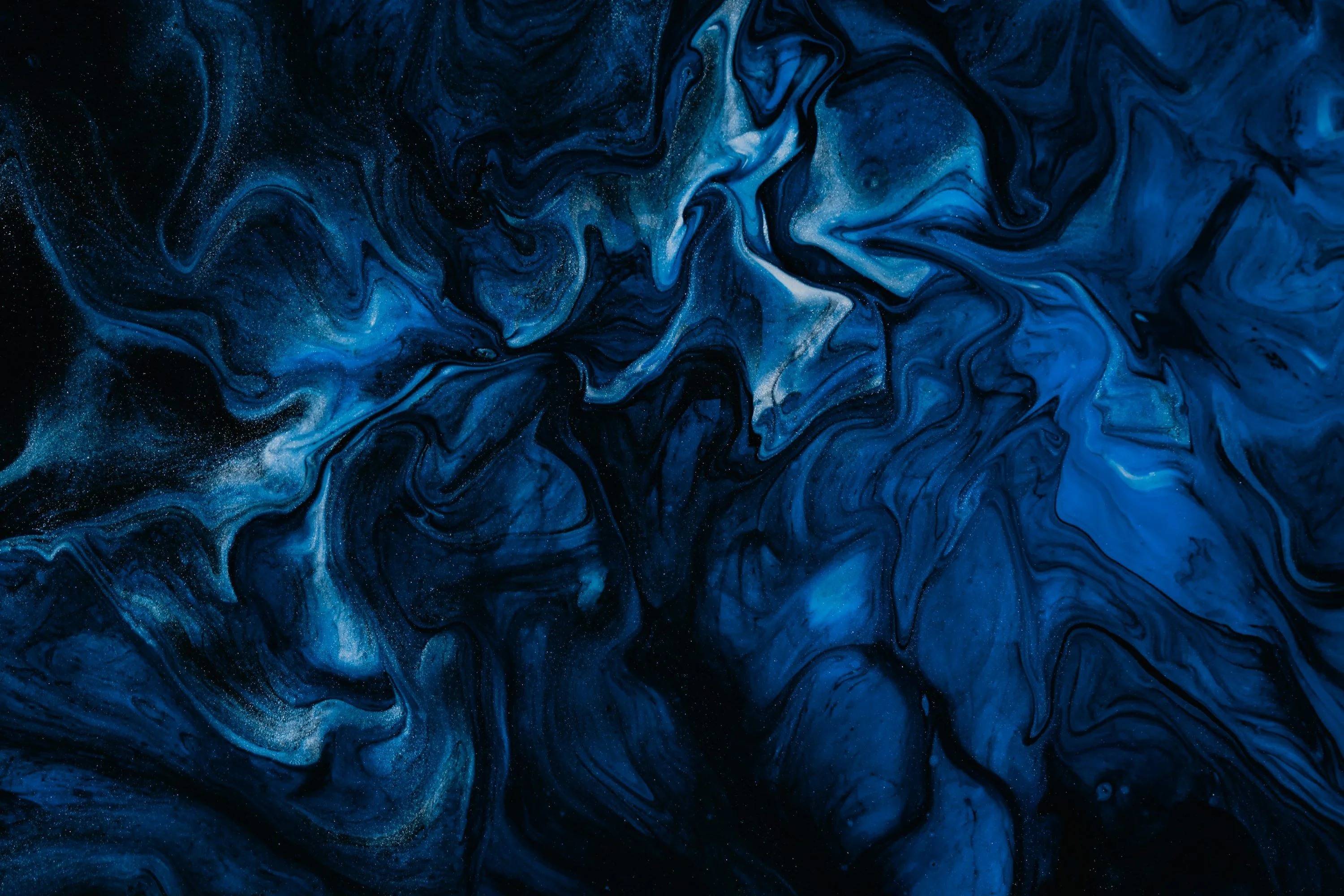 Ink swirls fold through each other in cobalt and navy, pale streaks marbling the upper left where the paint thins out.