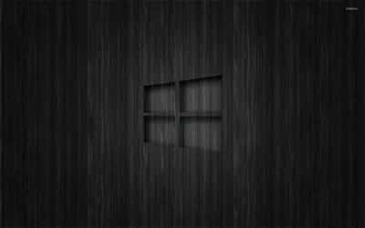 The Windows mark recessed into a vertically brushed dark panel, its inner edges catching light while the surface stays matte.