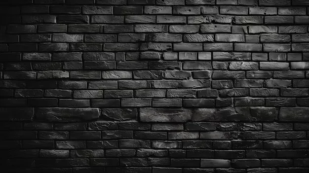Weathered black brickwork fills the frame with the light concentrated in the centre, all four corners fading into black.