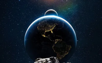 Seen from a rocky asteroid, the night side of the Americas sparkles with city lights while the Moon peeks over Earth's blue rim.