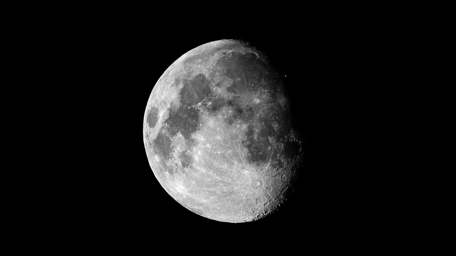 Every crater and ridge shows along the moon's shadowed edge, the black around it deep enough to hide screen bezels.