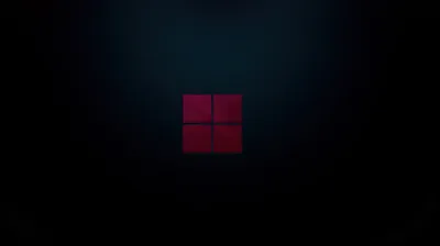 The four-pane Windows mark glows deep red at the centre of an almost black room, a faint cone of light opening above it.