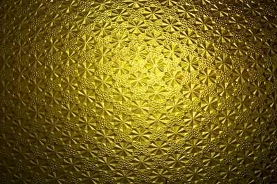 Rosettes pressed into a glass-like gold surface, light pooling at the centre and a heavy vignette pulling the edges toward black.