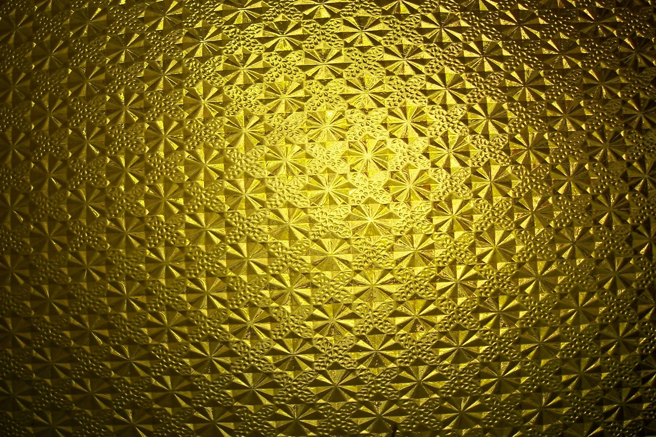Rosettes pressed into a glass-like gold surface, light pooling at the centre and a heavy vignette pulling the edges toward black.