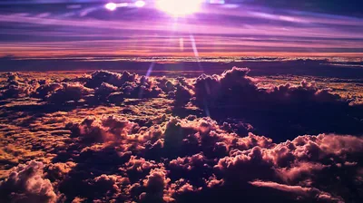 Seen from cruising altitude, a violet sun flare spikes above the horizon, washing the cloud deck below in magenta and deep purple.
