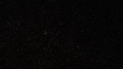 Thousands of small stars scatter thinly across black sky, dense in the middle band and sparse toward the corners.