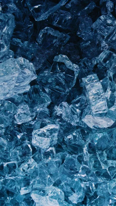 Chunks of shattered blue glass pack the frame edge to edge, brightest through the middle band, with deeper navy shadow settling along the top and bottom edges.