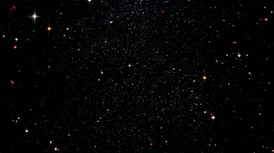 A crowded star field where red and orange stars stand out among the white, the densest band running vertically through the middle.