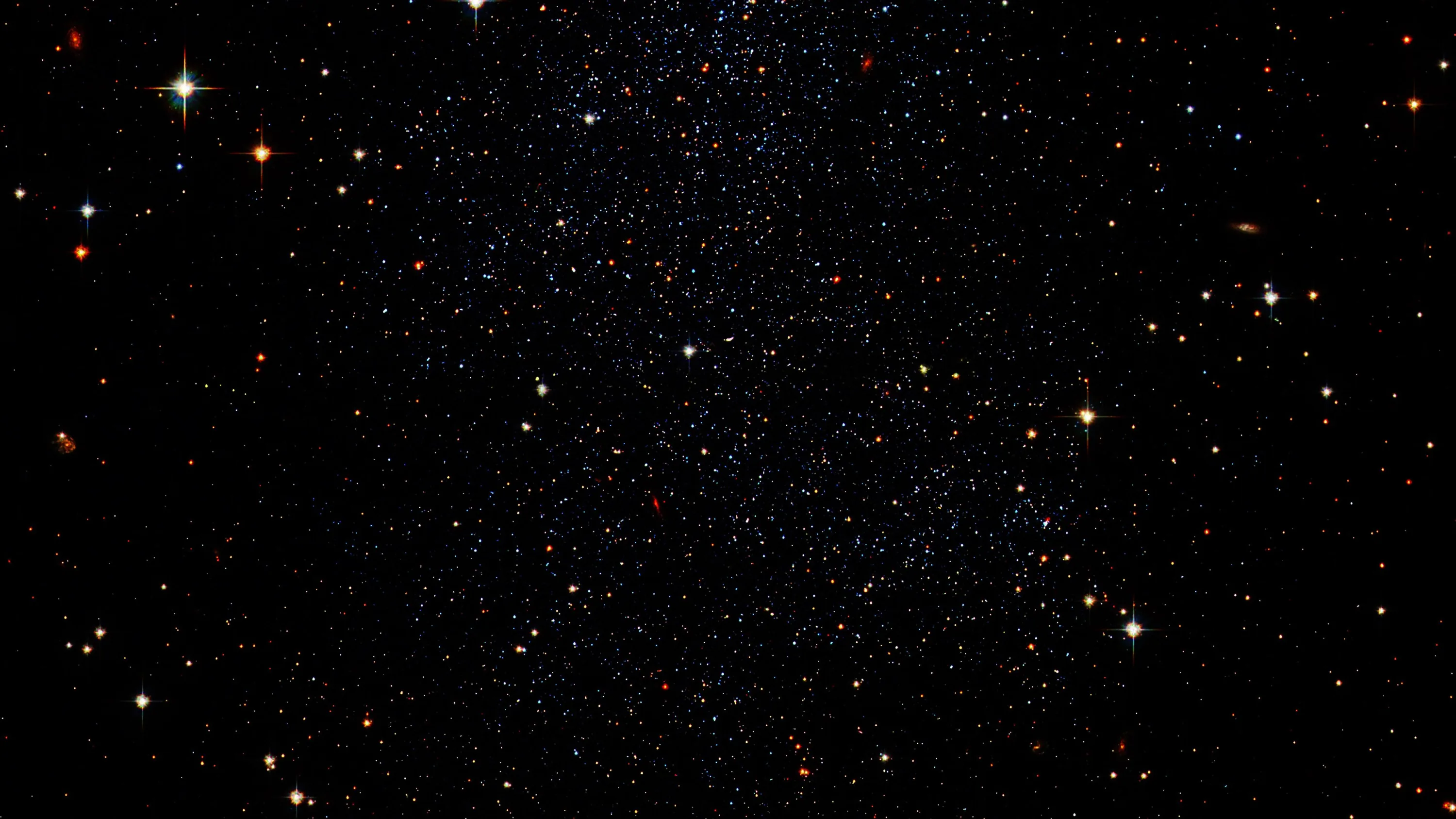 A crowded star field where red and orange stars stand out among the white, the densest band running vertically through the middle.