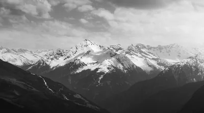 A range of snow-covered ridges runs across the middle distance in monochrome, the near slope in shadow.