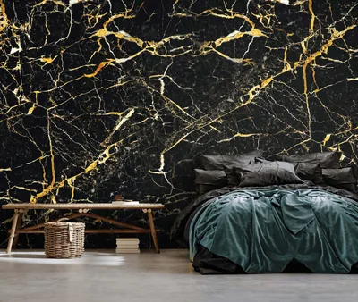 Gold veins fork across a black marble mural behind a bed in deep green bedding, with the lower left kept clear by a plain bench.