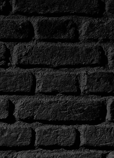 Five courses of coarse black brick shot up close, the pitted faces and deep mortar grooves lit evenly from the left.