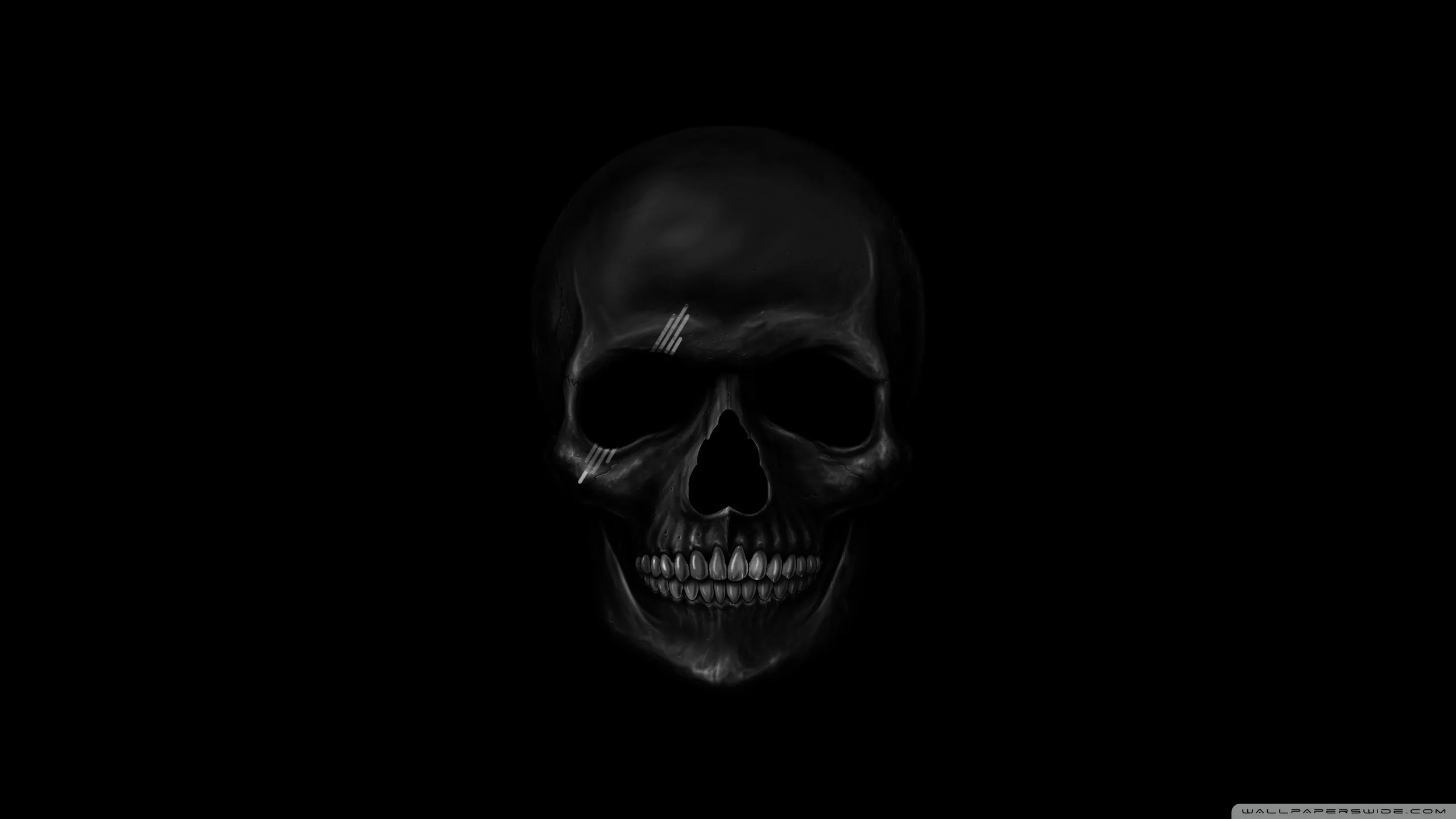 A skull surfaces just enough from the darkness to read, its teeth and brow the only clearly lit parts.