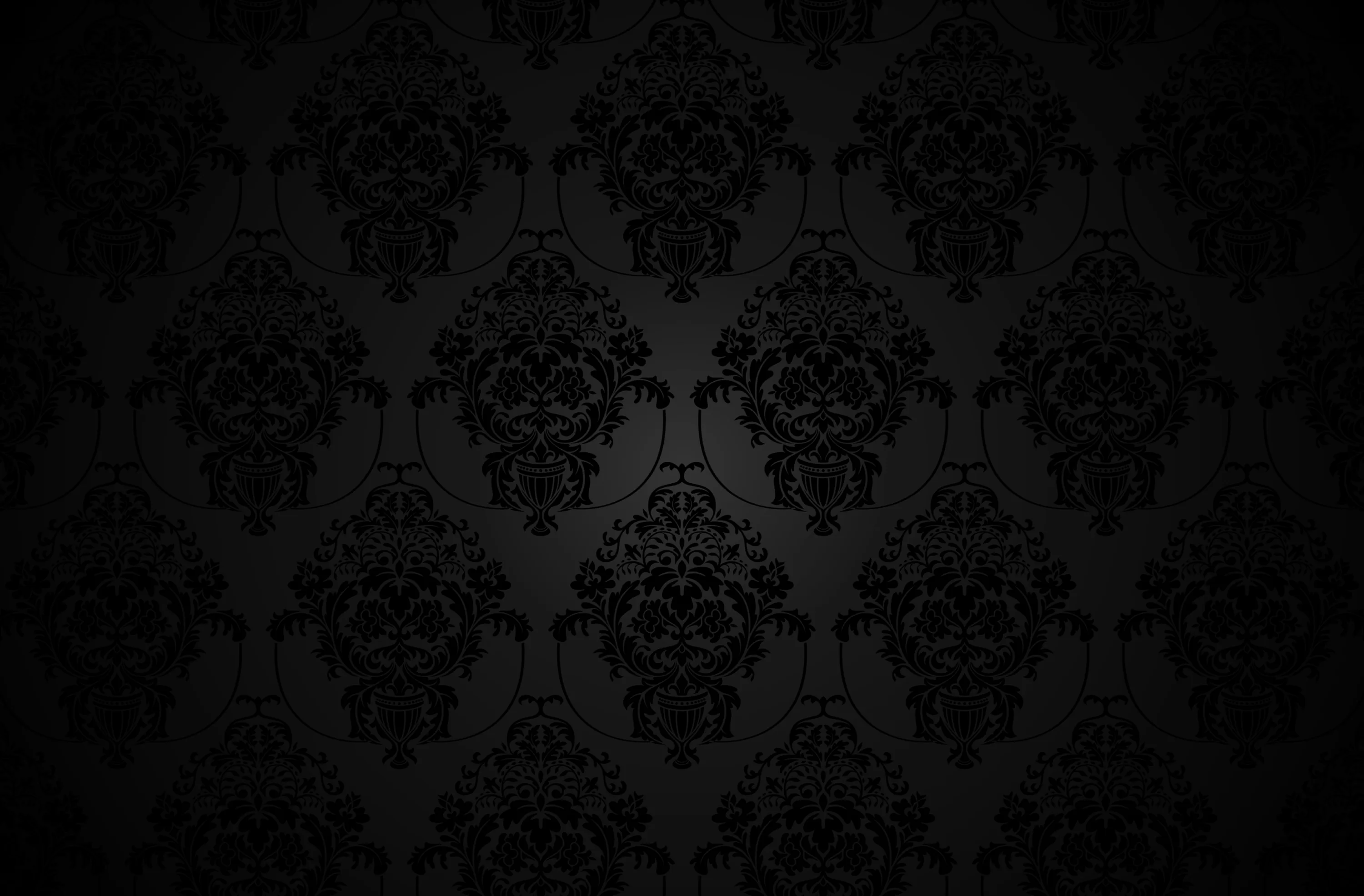 An ornate repeat covers the wall in charcoal on black, dropping to full darkness along the lower edge and corners.