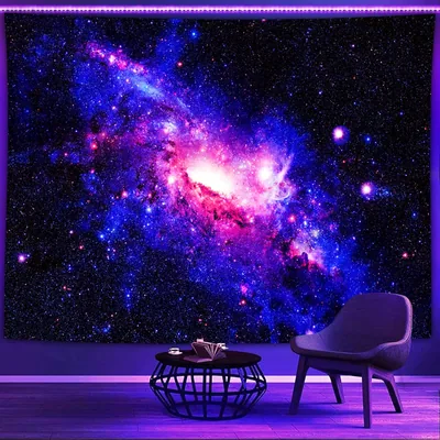 A purple-and-blue galaxy tapestry glows under blacklight behind a grey chair and wire coffee table, both tucked into the bottom-right corner.