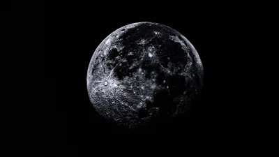 The full moon lit from the left in fine detail, its craters sharp against an empty black sky.