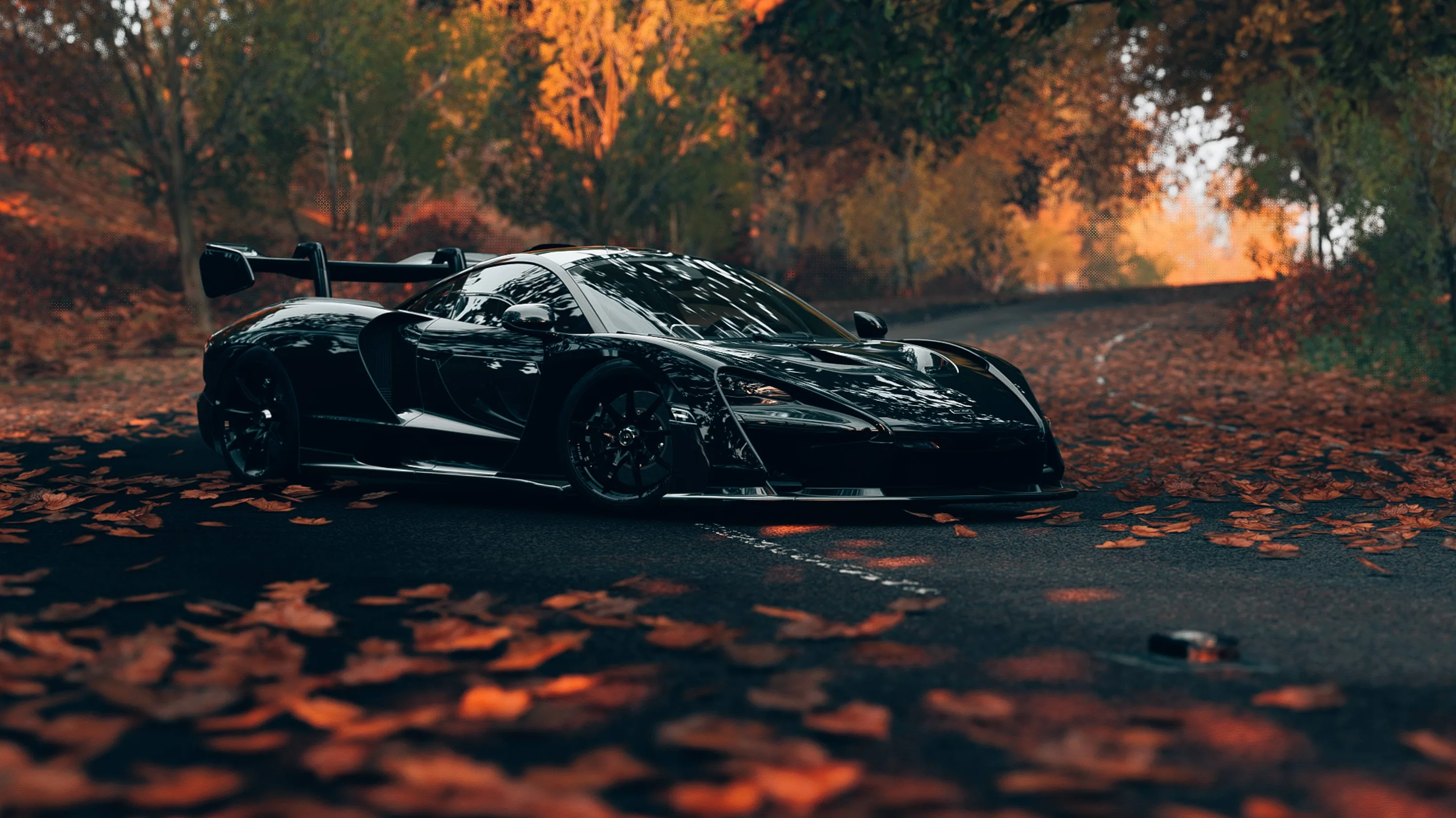 A long-tailed track car sits at an angle on wet asphalt strewn with fallen leaves, orange autumn trees filling the background and the foreground left soft.
