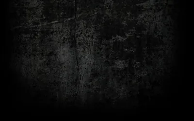 A weathered concrete surface holds its texture through the centre and drops off into full black at every edge.