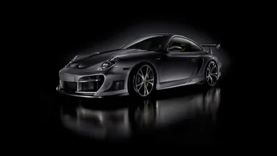 A widebody 911 with a tall rear wing stands on a mirror-black surface, silver-grey paint fading into pure black at both edges of the frame.