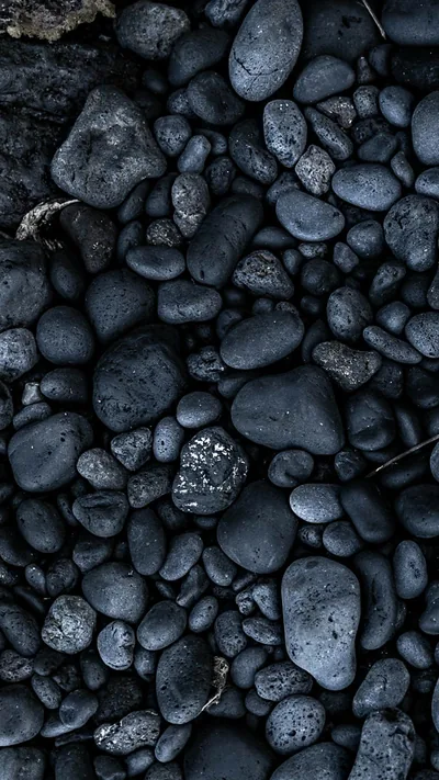 Smooth dark stones packed edge to edge, wet enough that each one carries a soft blue-grey highlight.