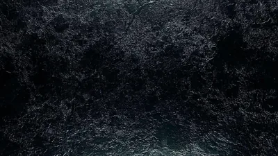 Churning water fills the frame from overhead, white foam breaking up the surface against near-black water.