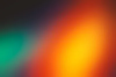 An amber flame of colour glows on the right while a smaller emerald patch answers from the left edge, both sinking into a dark, softly blurred field.