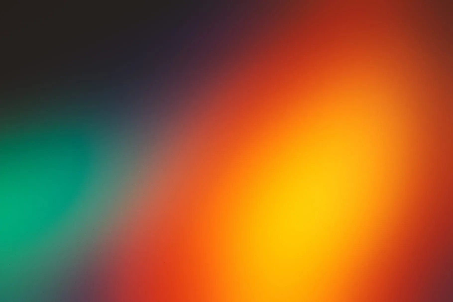 An amber flame of colour glows on the right while a smaller emerald patch answers from the left edge, both sinking into a dark, softly blurred field.