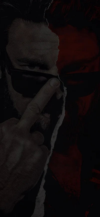 A man in dark sunglasses raises a finger to his lips, the frame split down the middle between deep shadow and a red wash.