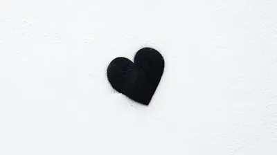 One small dark heart rests left of centre on a snow-white textured field, so the whole right side stays blank for widgets or icons.