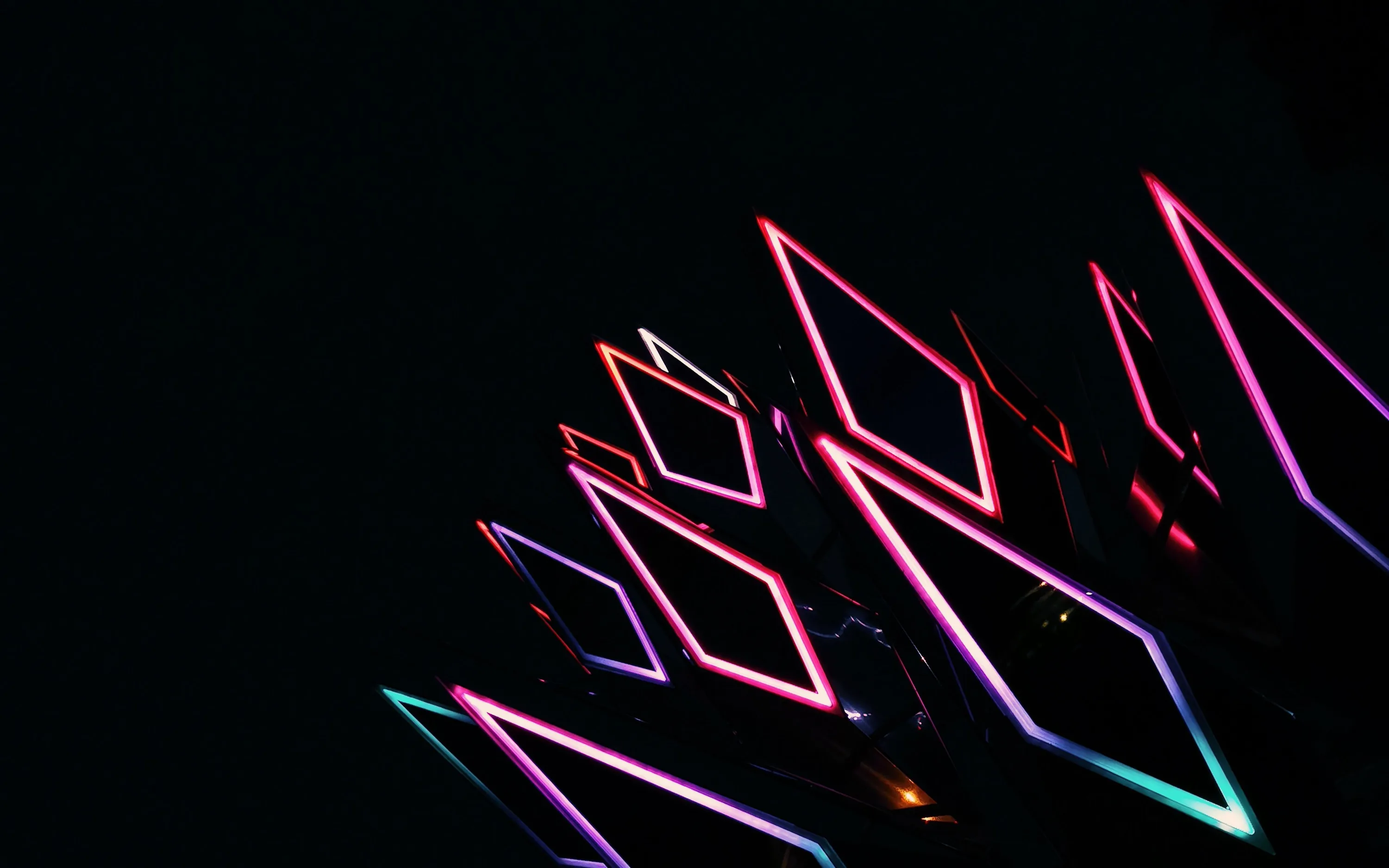 Bright pink, blue and violet diamond shapes stack diagonally across the frame, the rest left black.