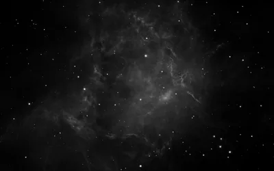 A soft monochrome nebula drifts through the middle of the frame with scattered stars, the edges left almost fully black.