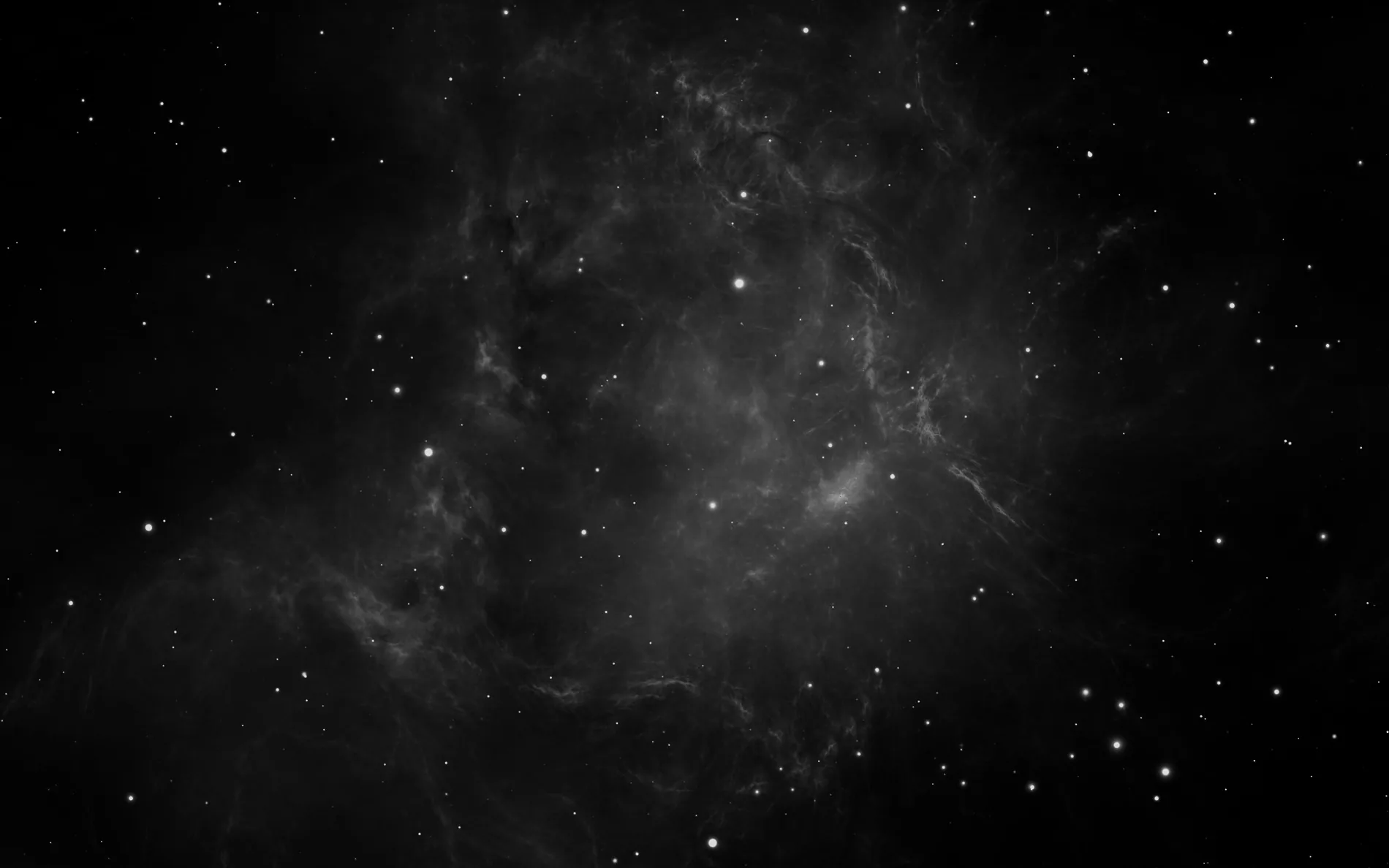 A soft monochrome nebula drifts through the middle of the frame with scattered stars, the edges left almost fully black.
