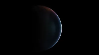 A planet hangs off-centre against empty space, a thin rim of rust and pale blue along its upper edge, the rest in shadow.