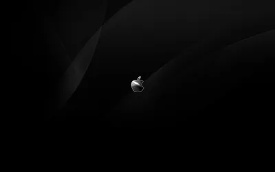 A small chrome Apple logo sits just off centre, faint curved shadows sweeping behind it across an otherwise black desktop frame.