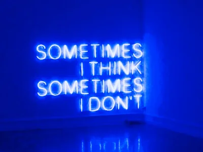 A neon sign reading Sometimes I Think Sometimes I Don't burns bright blue in the corner of a room, washing both walls and the glossy floor in blue.