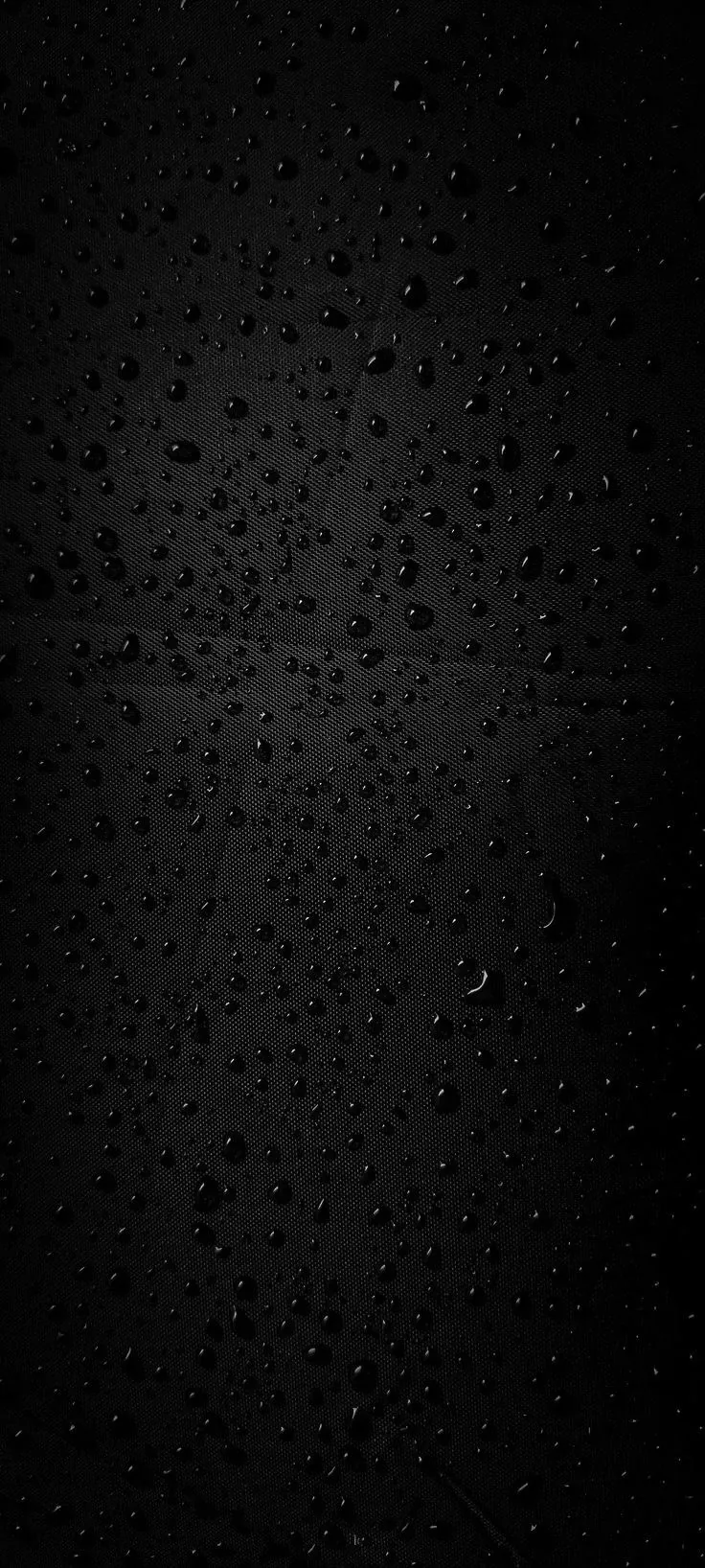Fine beads of water cling to a black pane, denser through the middle and thinning out towards the corners.