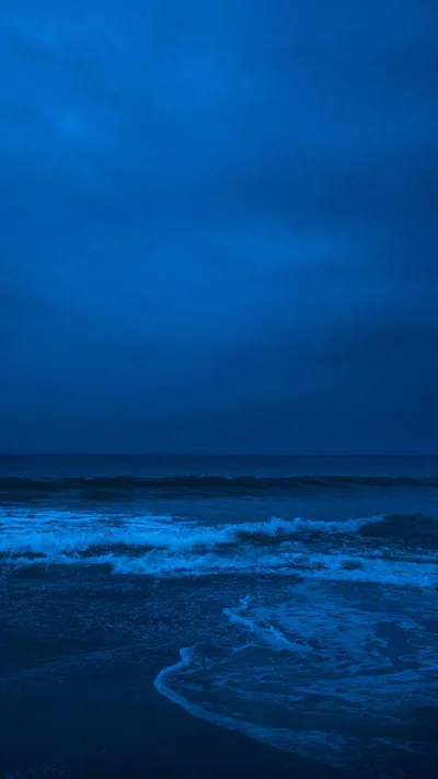 A heavy blue dusk sky takes up the top two thirds with nothing in it, leaving all the icon space clear above a faint line of surf.