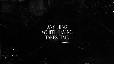 White serif lettering centred on a scuffed black plaster wall, faint scratches and dust flecks catching light around the edges.