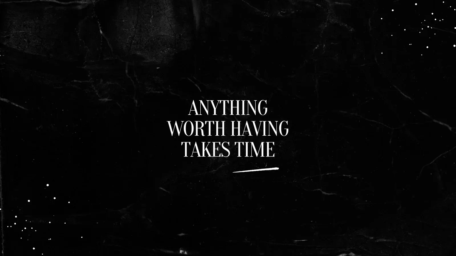 White serif lettering centred on a scuffed black plaster wall, faint scratches and dust flecks catching light around the edges.