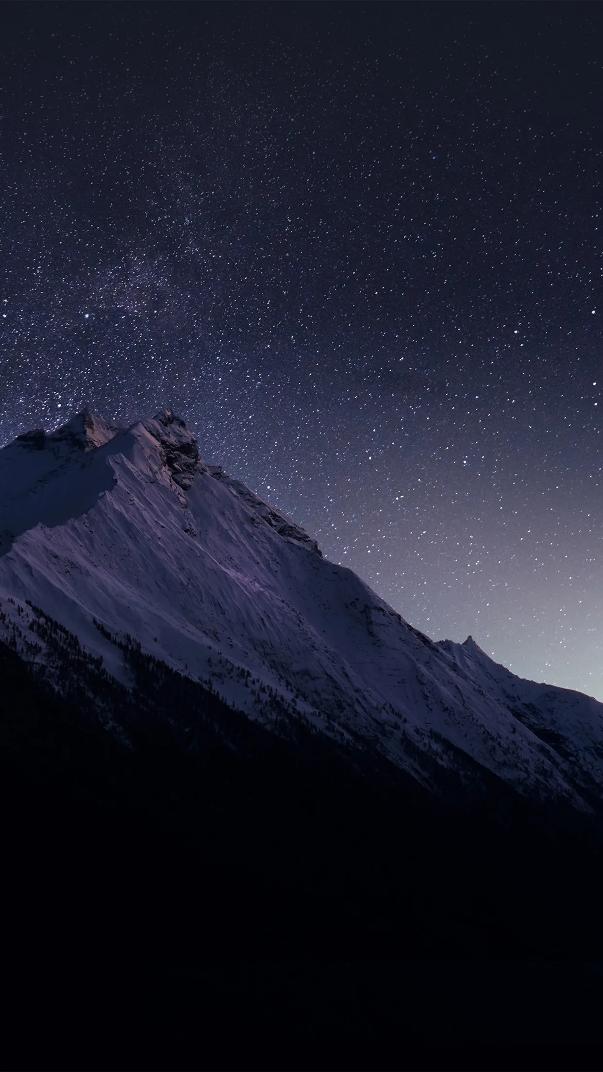 A snowy ridgeline sits below a sky dusted with stars, the dark navy upper two-thirds keeping the lock-screen clock legible.