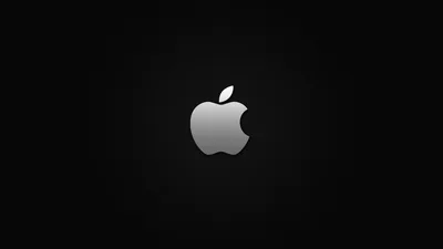 A silver Apple mark sits in the middle of a wide black frame, a soft halo of grey light spreading out behind it and fading at the corners.