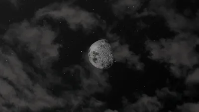 A cratered moon shows through a gap in heavy cloud, the sky around it black except for a few stars.