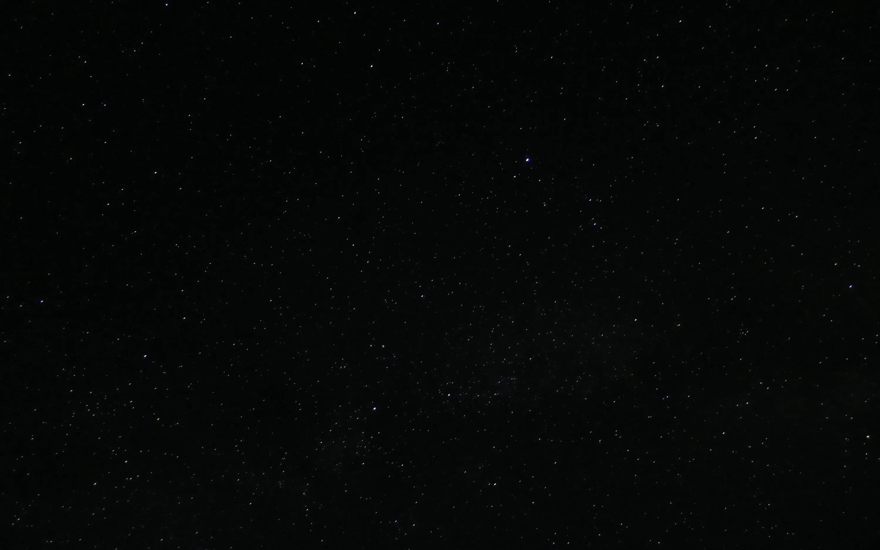 Fine white stars spread thinly over near-black sky, denser through the middle band and almost empty along the bottom corners.