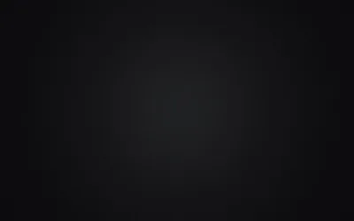 An empty studio wall lit from the middle, a wide grey pool of light fading evenly outward until the corners go fully black.